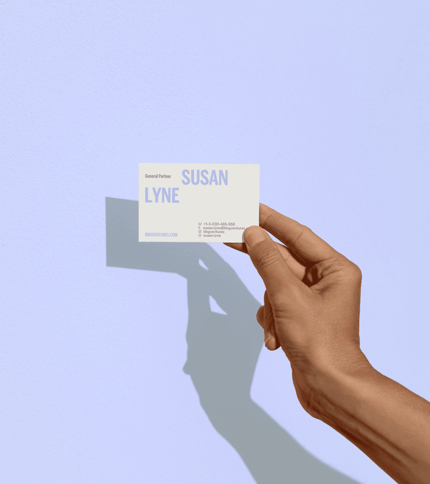 Hand holding business card in front of purple background