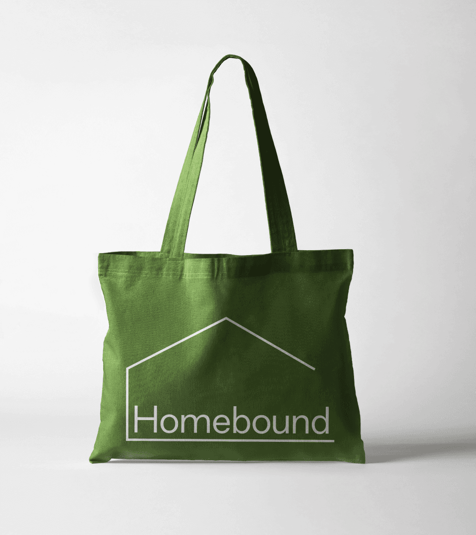 A green canvas tote bag printed with the Homebound house wordmark.