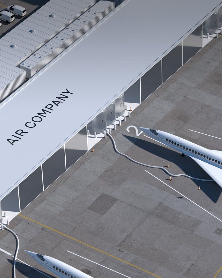 Aerial view of the Air Company hangar — a long white industrial building with the AIR COMPANY wordmark across one side, white aircraft parked along the apron.