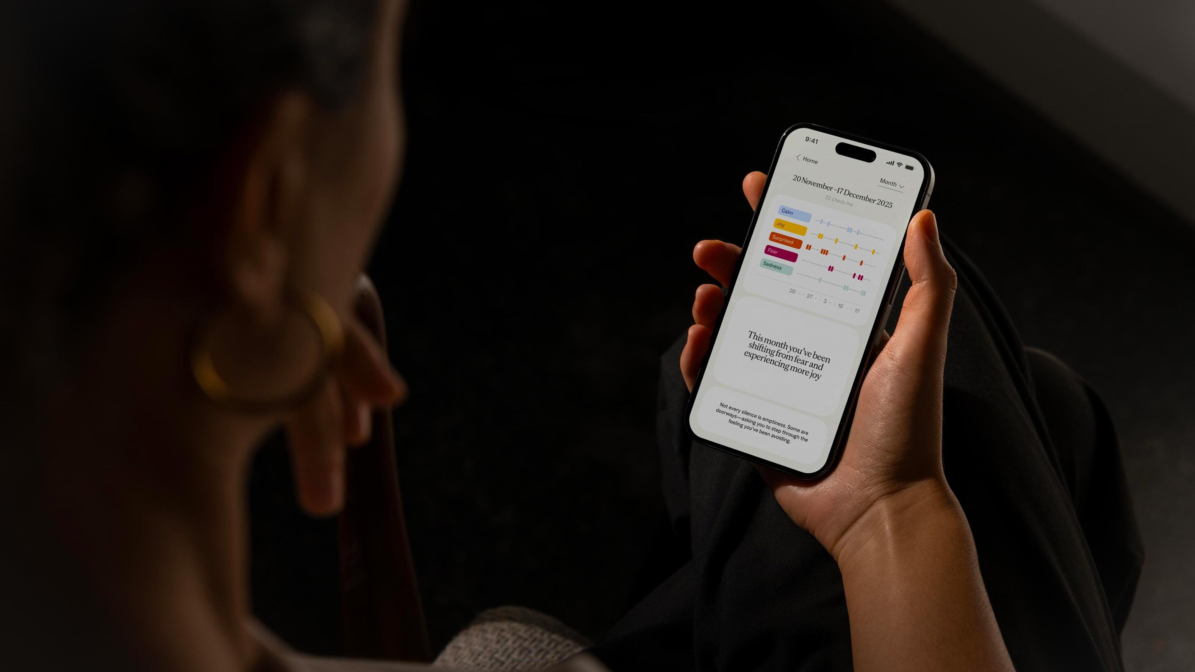 A user holding a phone showing Thea’s trends screen with weekly emotion insights