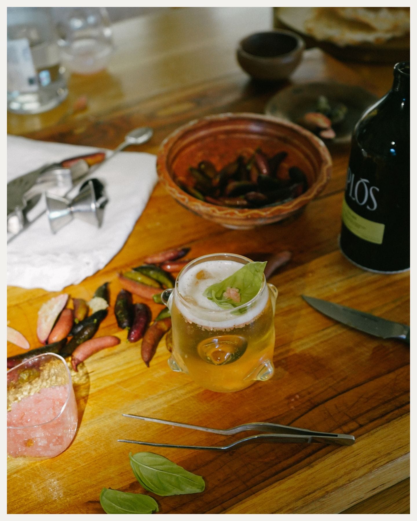A cocktail surrounded by bartender’s tools and ingredients.