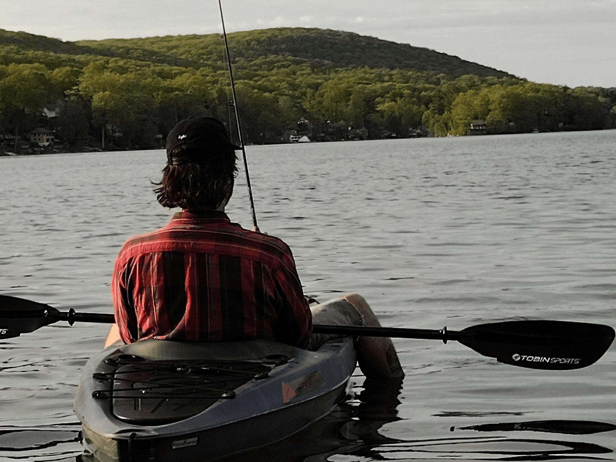 Person paddling a kayak on a calm lake at dusk, photographed on a Light Phone III.
